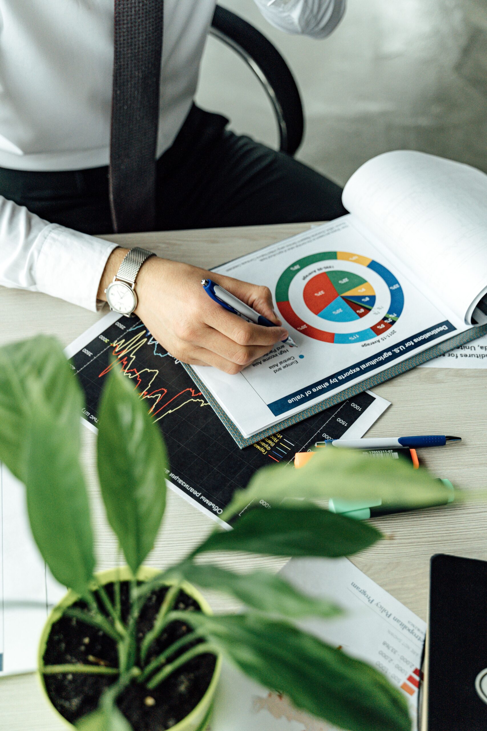 Business professional analyzing financial graphs and charts at an office desk with a laptop.
