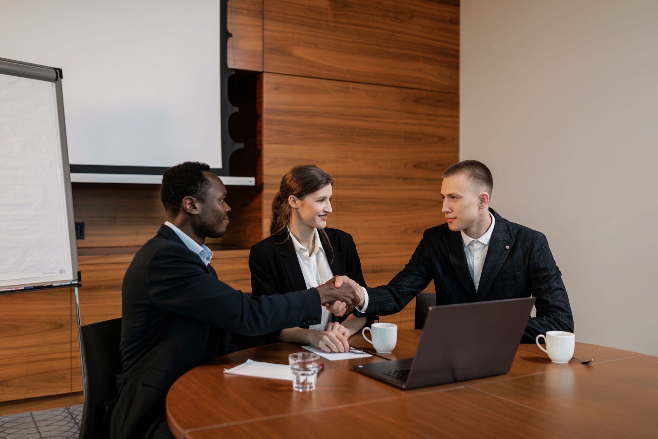 Professionals shaking hands at a business meeting, showcasing teamwork and collaboration.